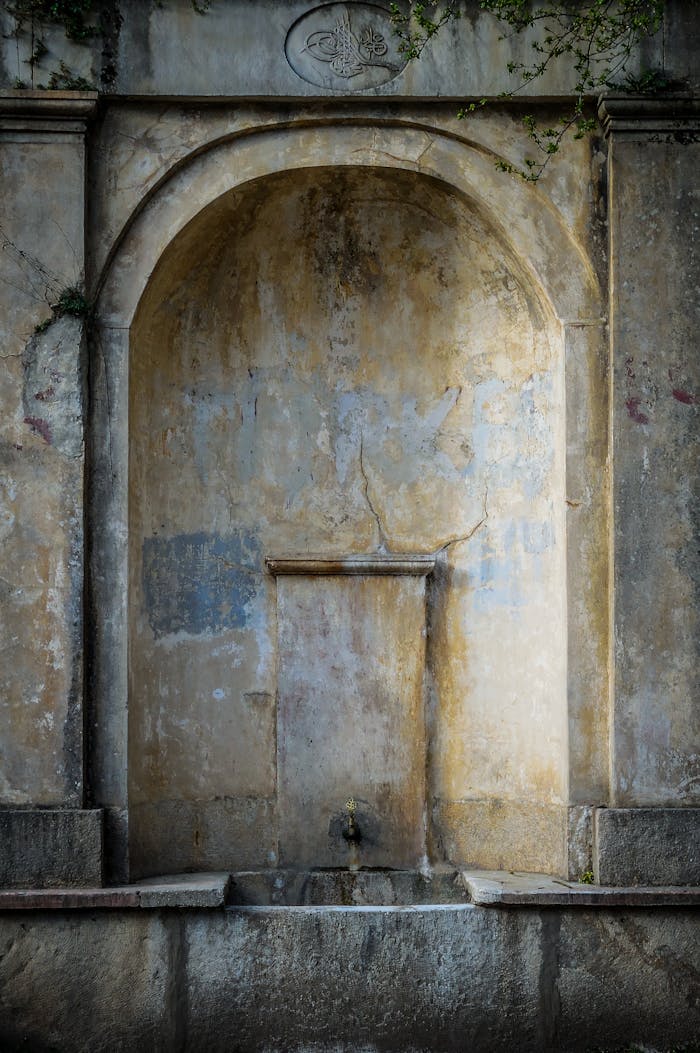 Home A weathered stone fountain with a gothic arch in Istanbul. Captures the beauty of ancient architecture.