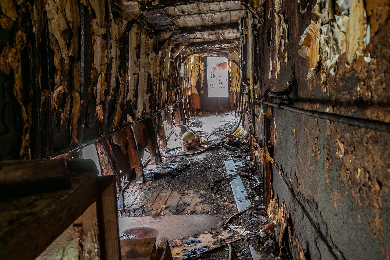 Explore the eerie decay and rust of an abandoned hallway with peeling walls.